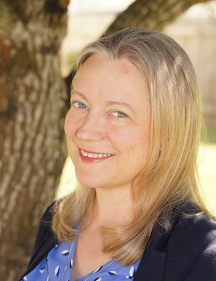 woman with blonde hair, wearing a blue suit, smiling outdoors
