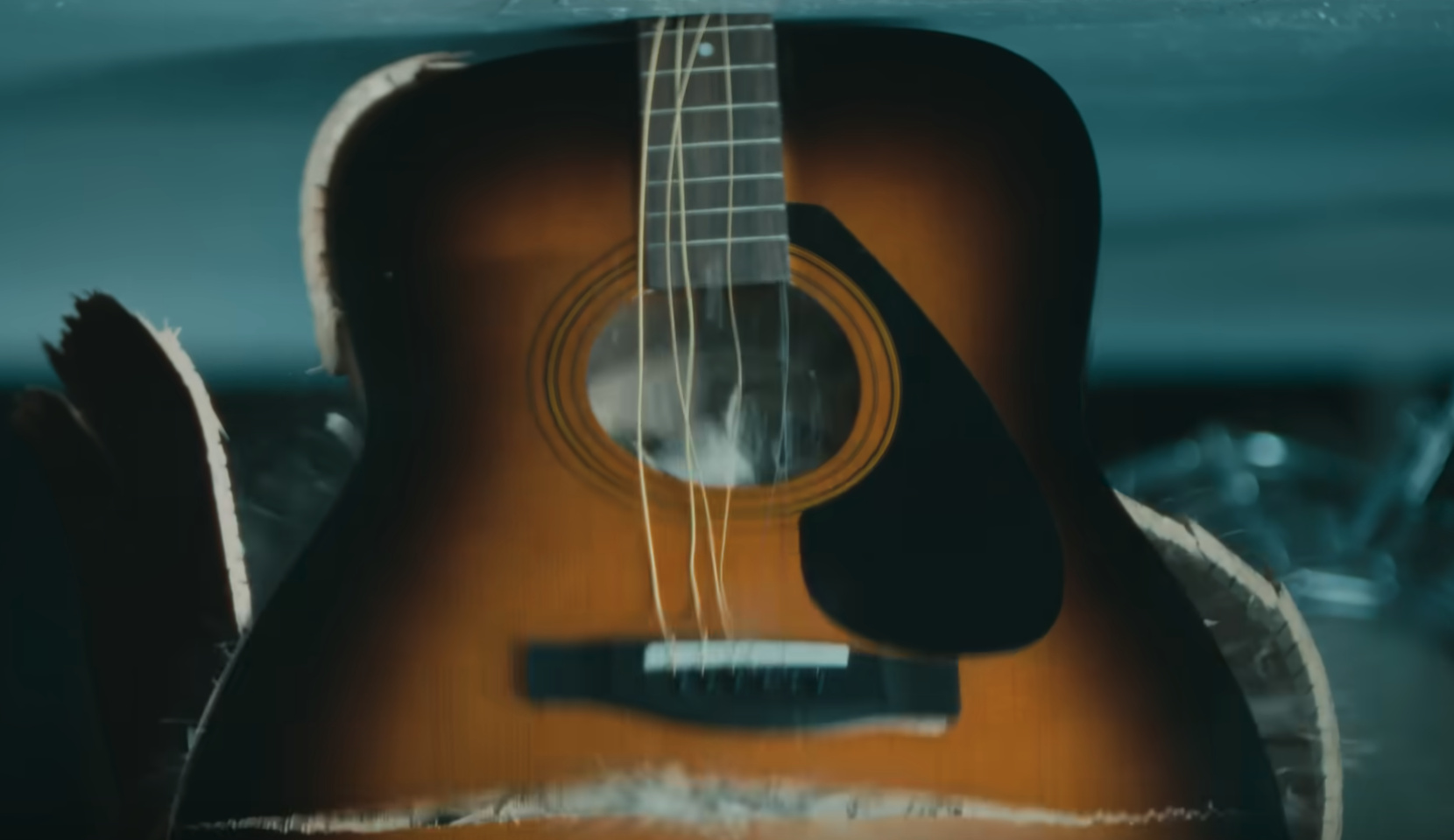 A beautiful acoustic guitar being crushed by a hydraulic press in an Apple ad.